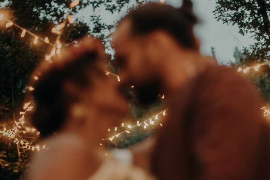 couple marié qui s'embrasse sous une guirlande au domaine de Petiosse dans les Landes
